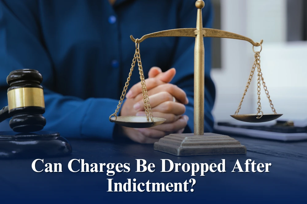 An image showing person wearing a dark blue dress shirt sitting and placing his clasped hands on top of the table where a weighing scale and a gavel is placed.